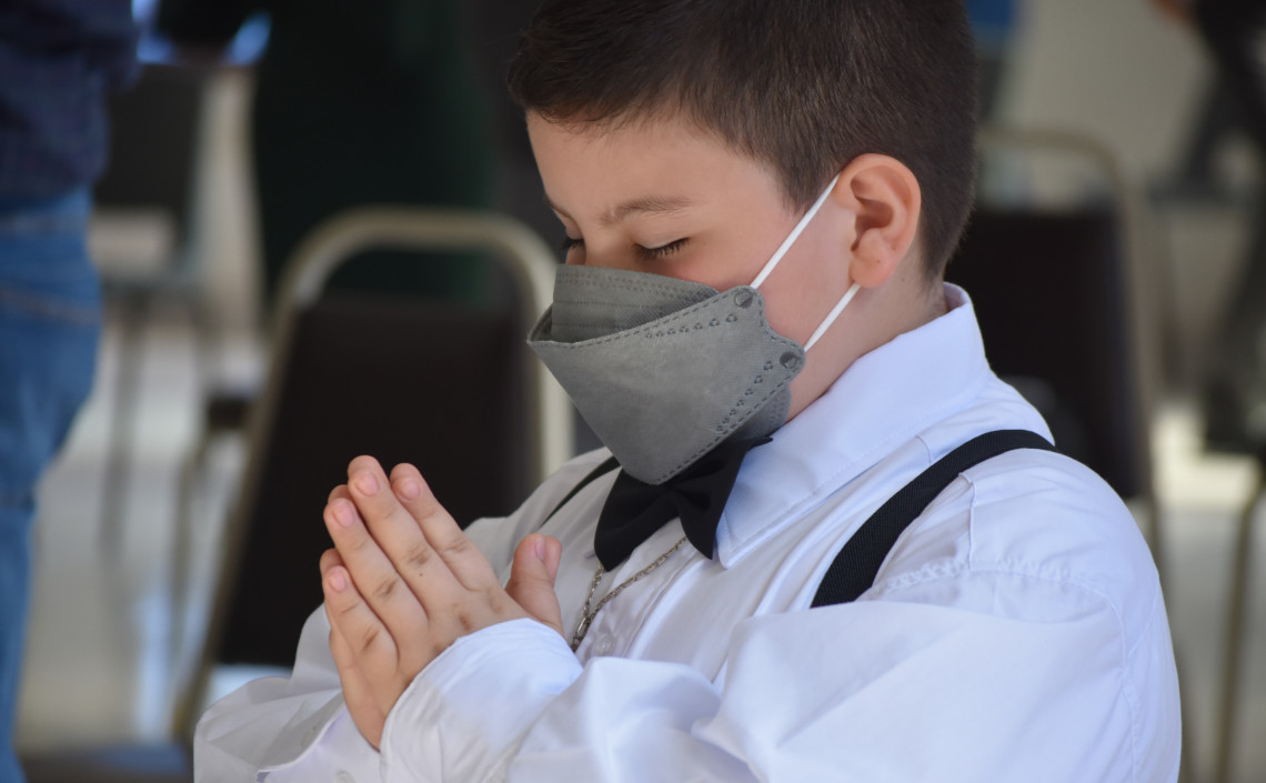 Niño con los ojos cerrados en posición de oración