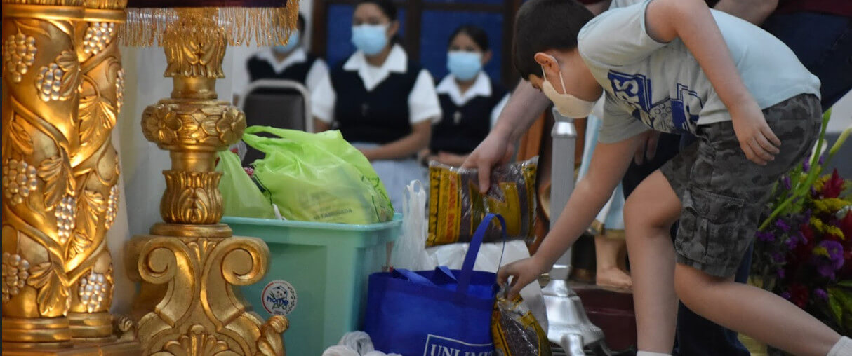 Niño dejando donación de comida en el Altar